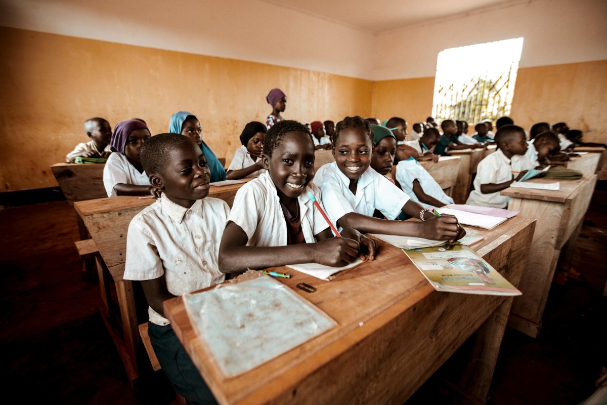 Qui sommes nous? Jeunes enfants souriants devant une école soutenue par l'association